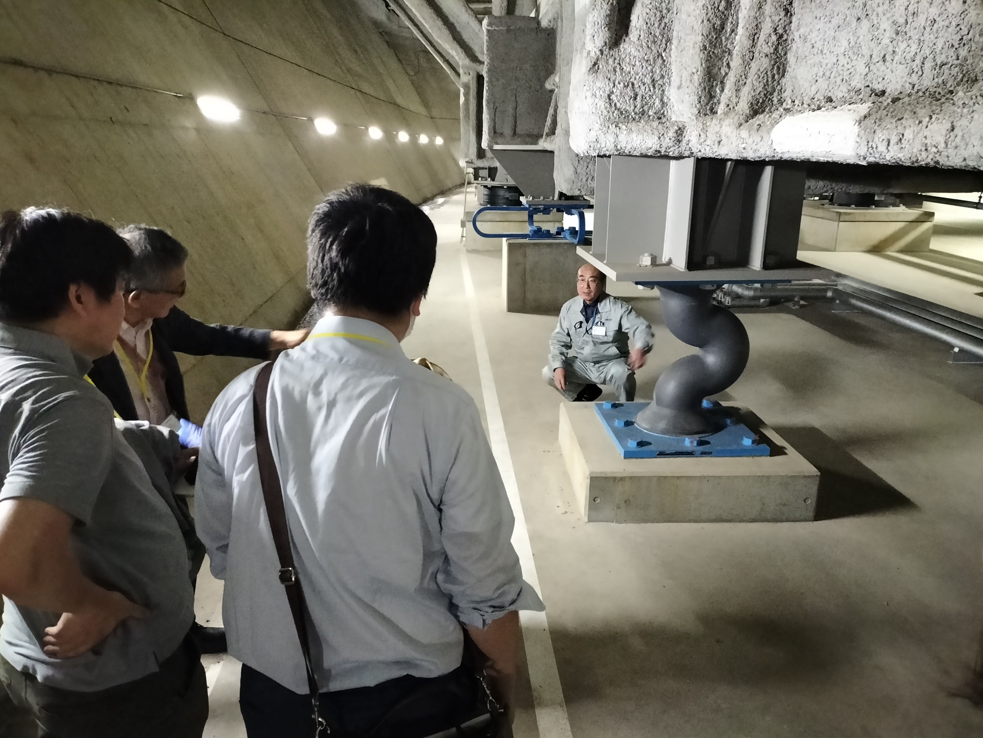 図2　科学技術振興機構（JST）のウェブマガジン「Science
                  Window」で地下の免震構造を取材。U型鋼製ダンパーの説明をする運用技術部門の松下聡上級テクニカルスタッフ