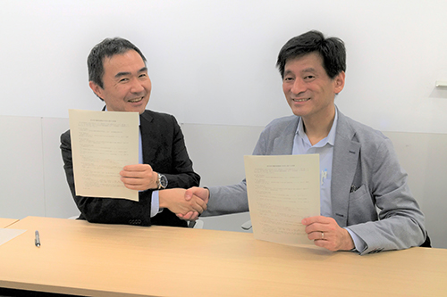 写真：覚書を持ち握手をする新庄氏と松岡氏